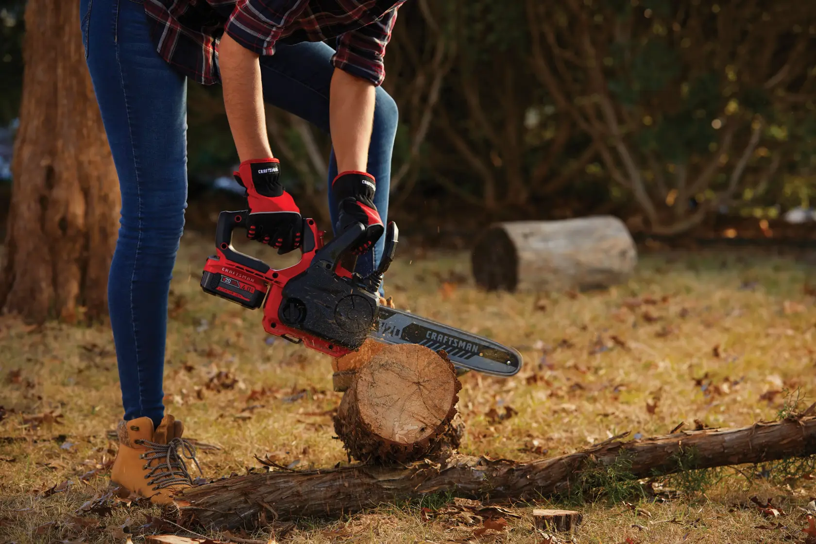 Woman using the CRAFTSMAN Cordless 12-Inch Compact Chainsaw to cut a log