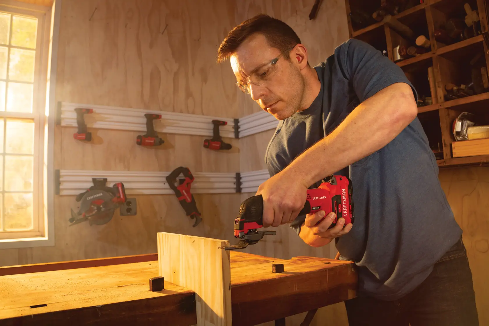 Cordless oscillating tool kit being used on wooden plank.