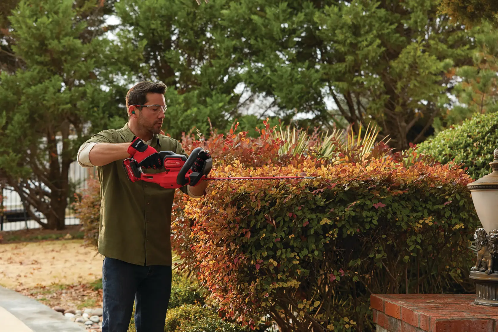 Cordless 22 inch hedge trimmer kit 2 ampere hours being used to level hedge.