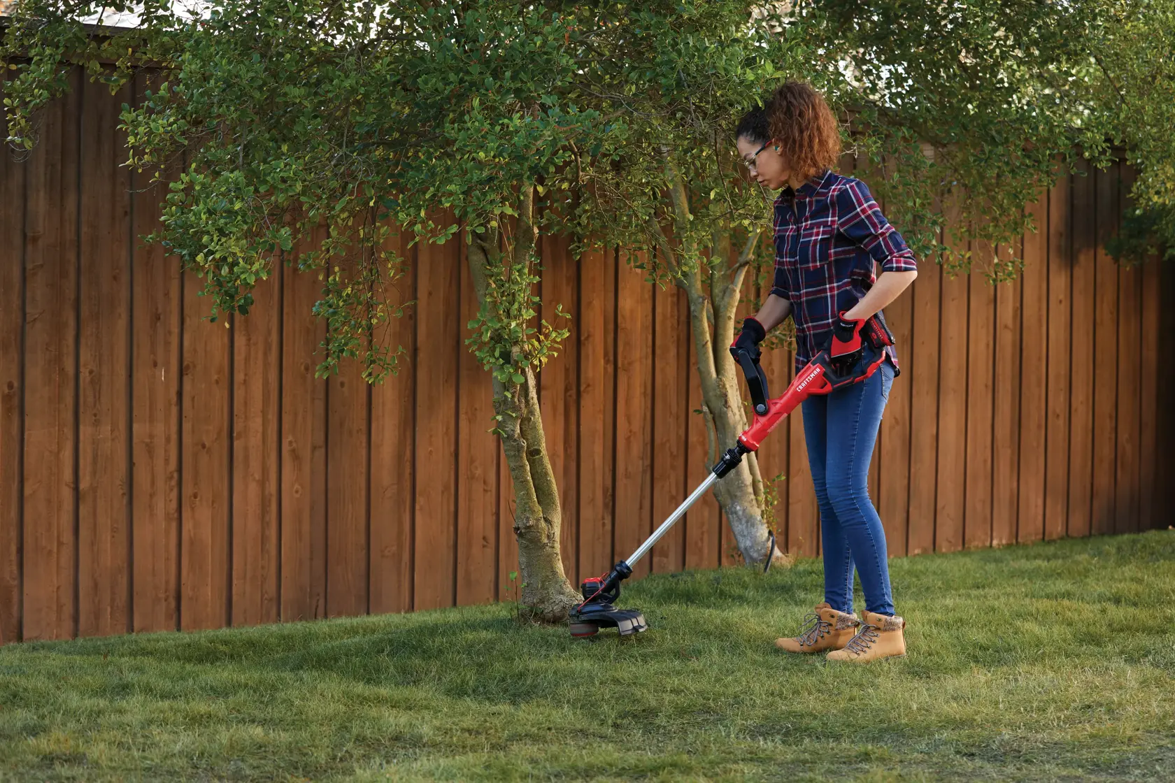 Woman using CRAFTSMAN V20 WEEDWACKER(R) Cordless String Trimmer around tree