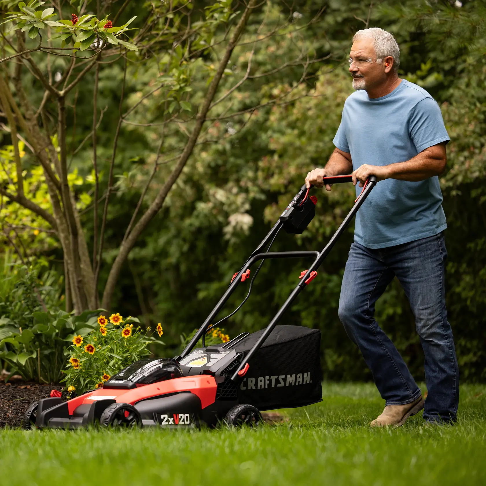 2 x 20 volt 20 inch brushless cordless push mower being used for mowing under bench.