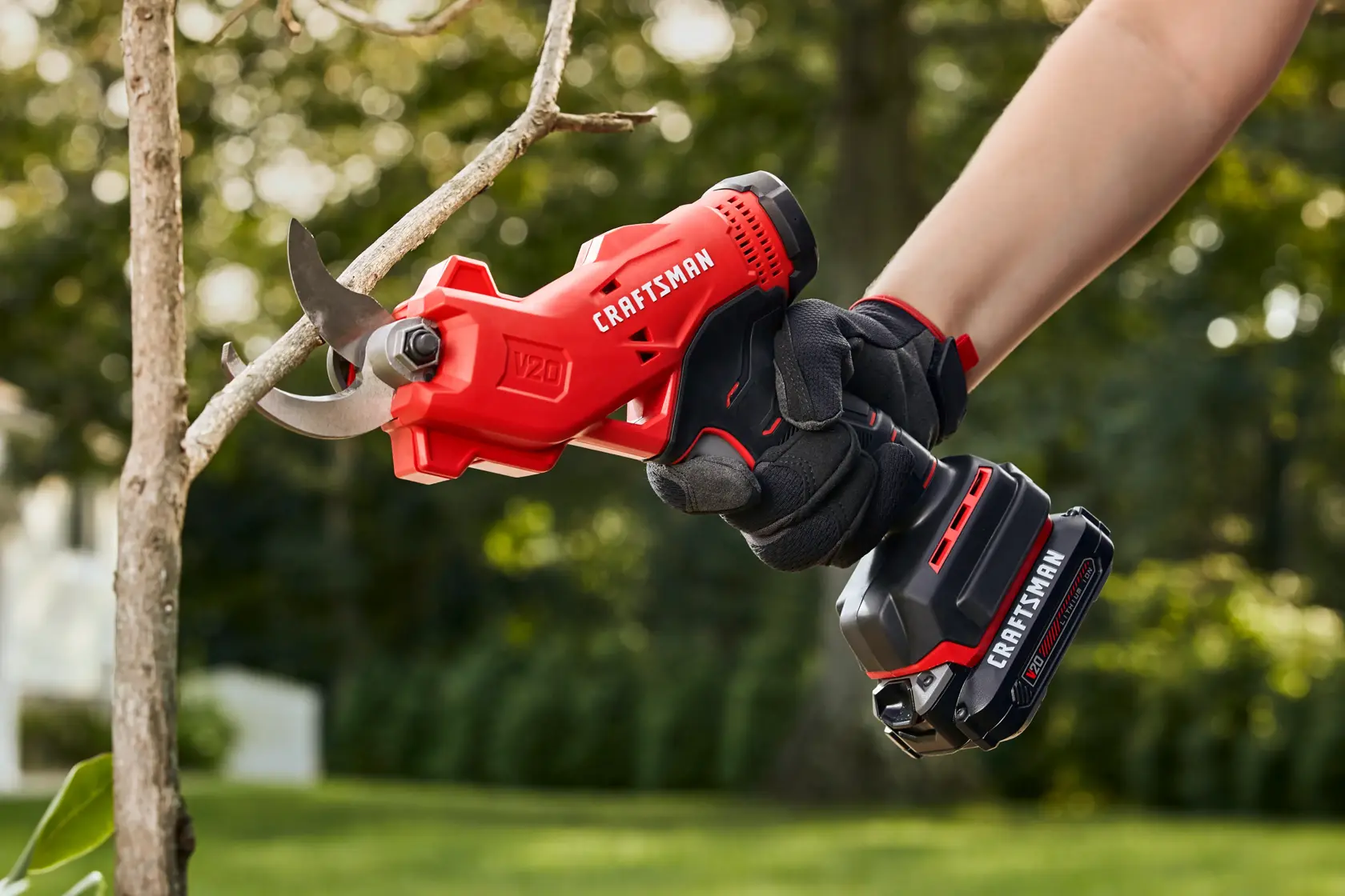 20 volt cordless pruner kit being used by a person to cut a branch in the garden.