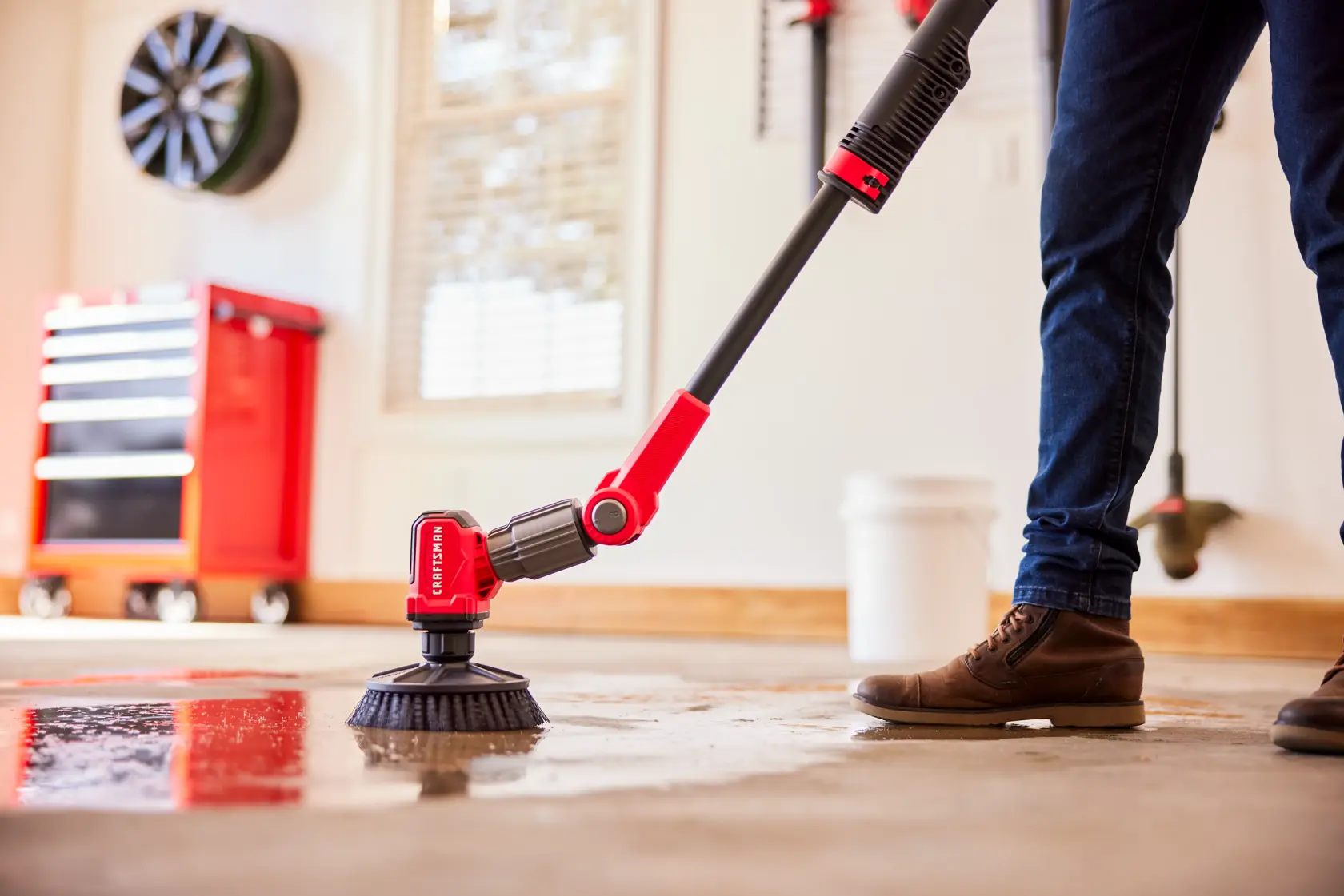 Side view of male cleaning garage floor with V20 Scubber 