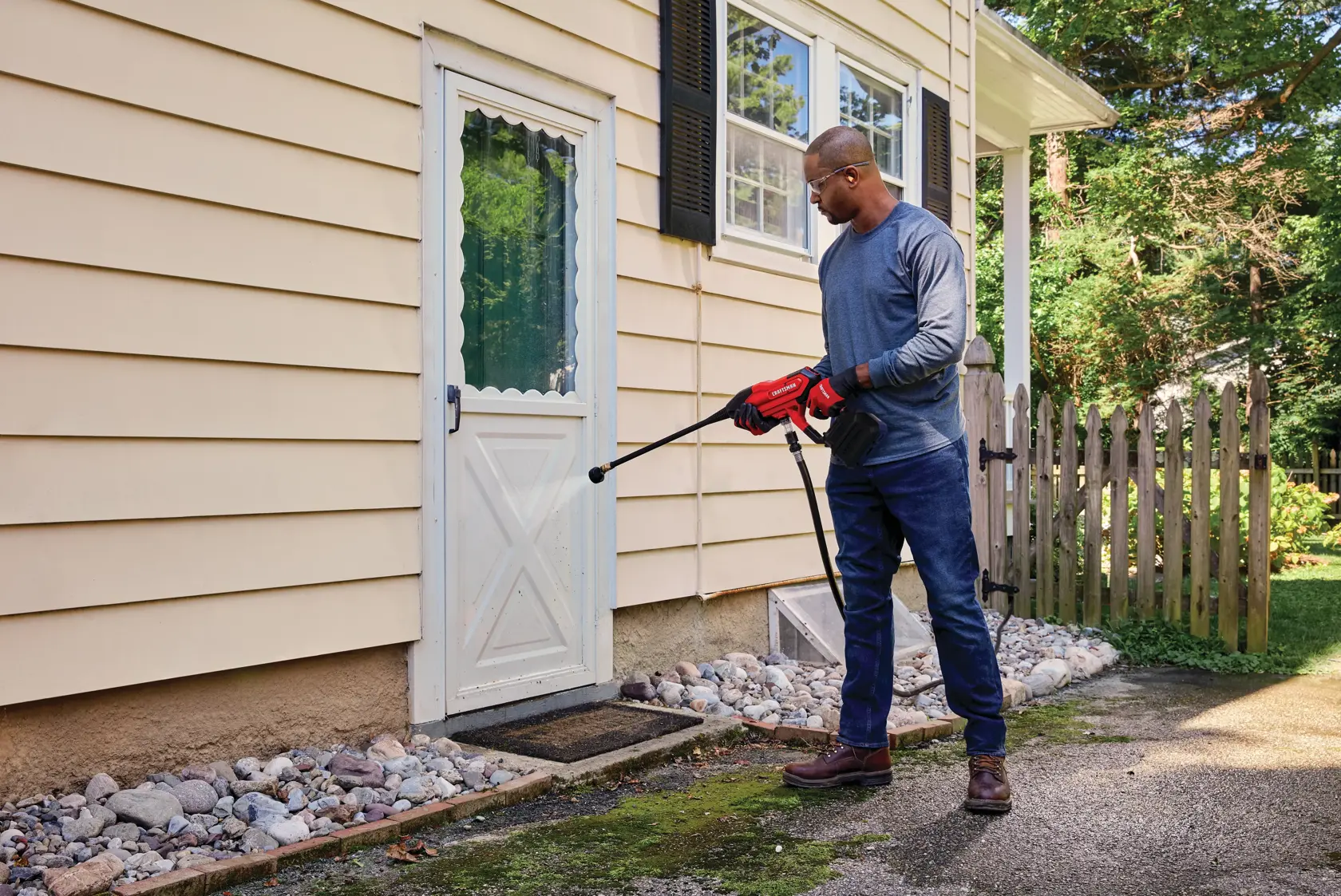 20 volt cordless 350 max P S I power cleaner kit being used by a person to clean a door outside.