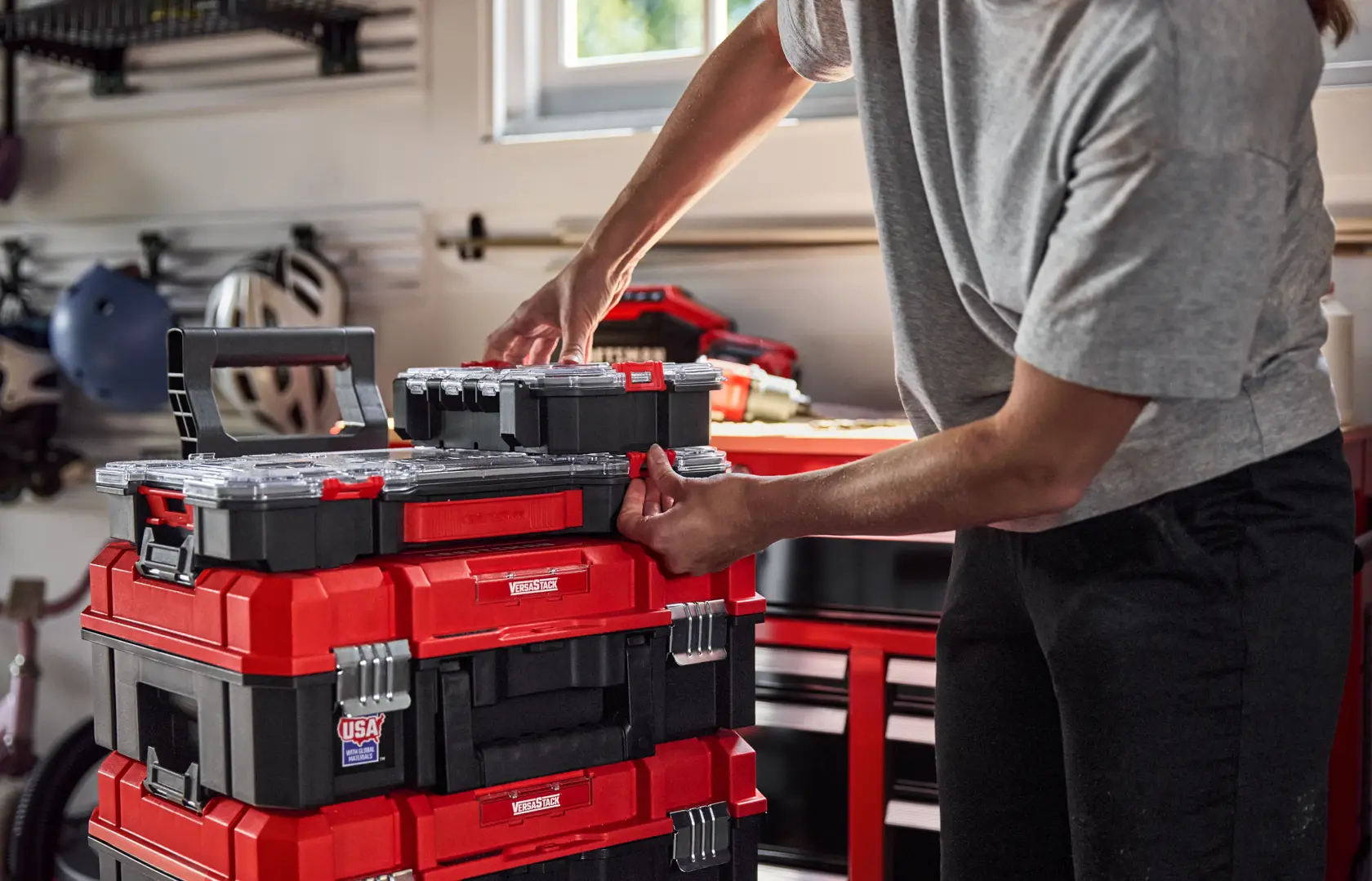 Photo of Craftsman stackable toolboxes CMST17828 in a garage, red and black, being organized by a person.