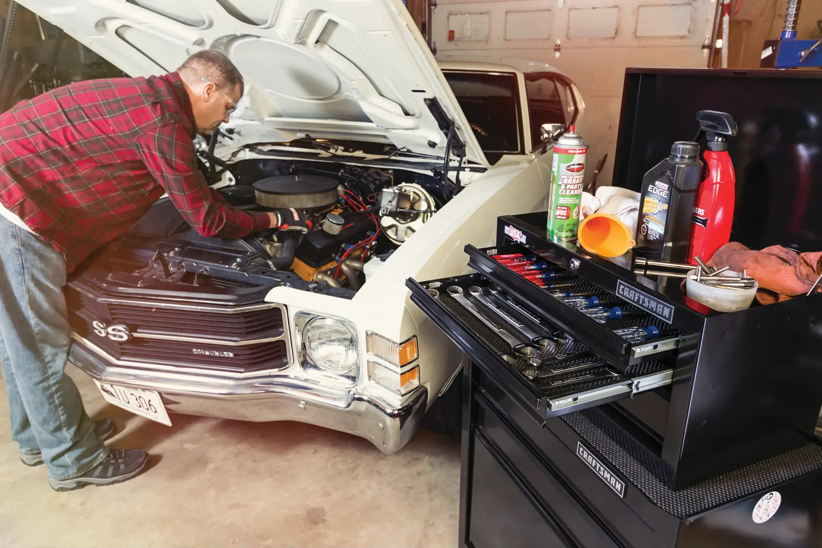 Photo of CRAFTSMAN CMST22653BK tool chest with open drawers and tools next to classic car being serviced.