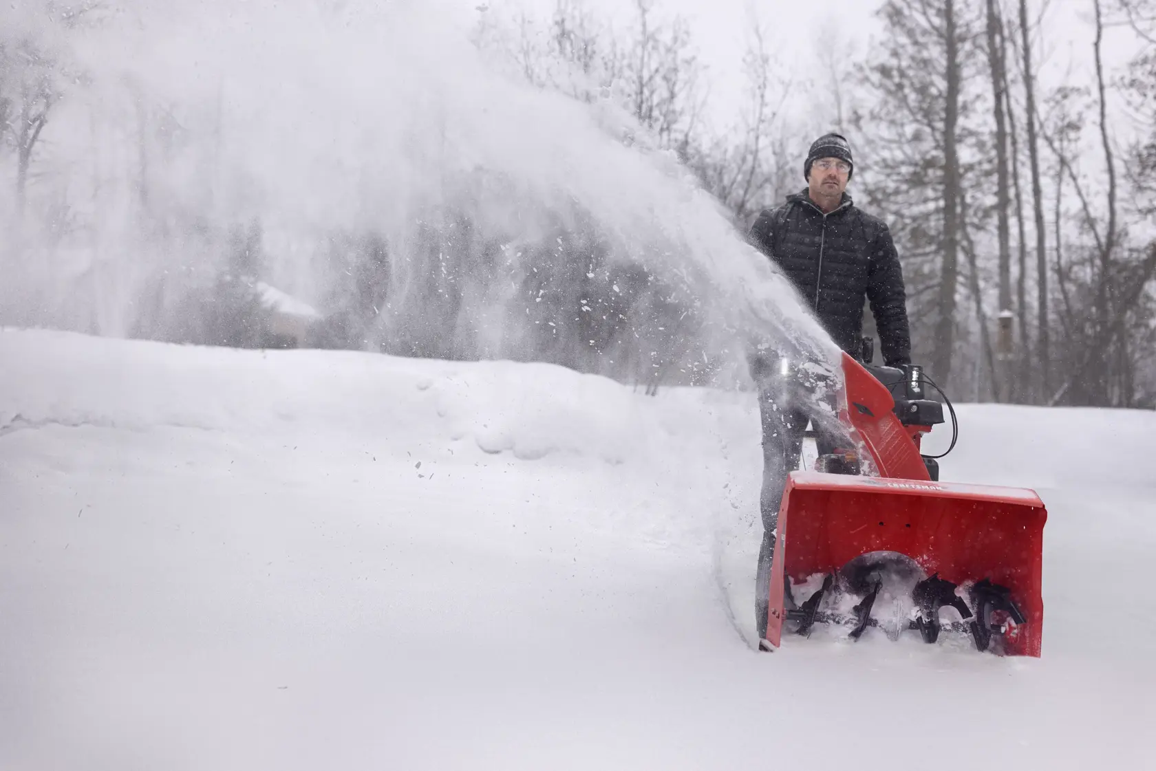 CRAFTSMAN Select 26 Snowblower zoomed out clearing snow from driveway trees in background