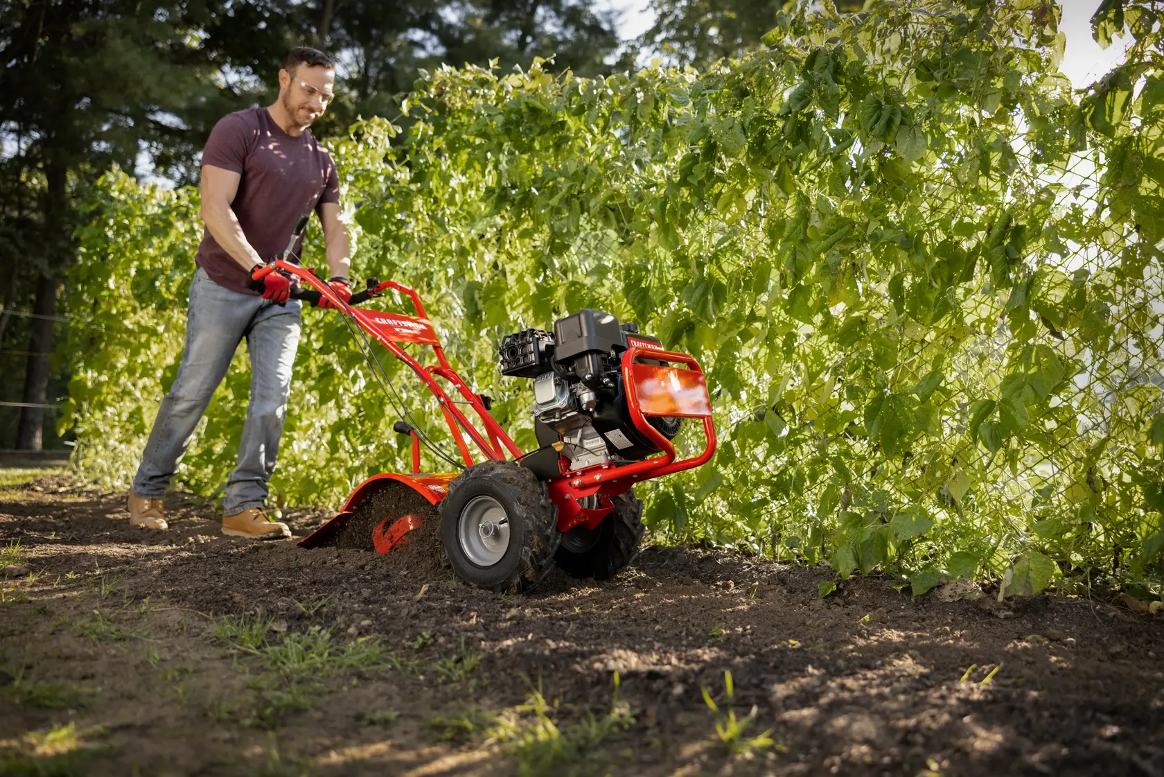 CRAFTSMAN 16-in. 208cc Gas Rear Tine Tiller tilling garden area with trees in background